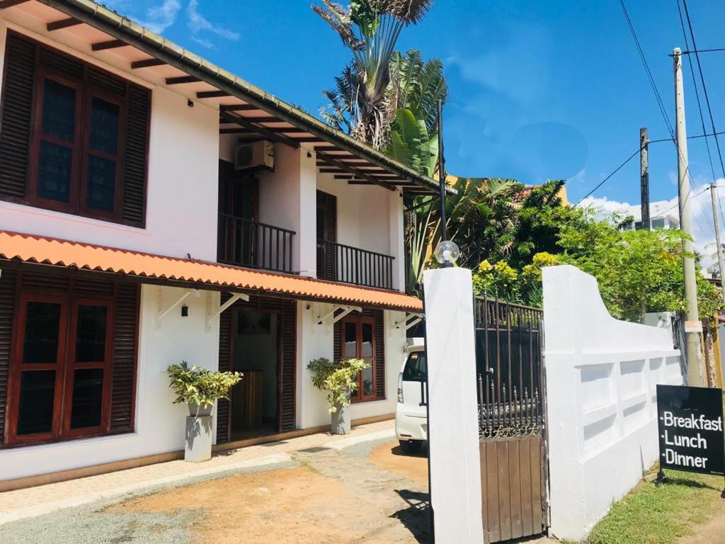 a white house with a gate and a fence at Tamaro Beach Resort in Hikkaduwa