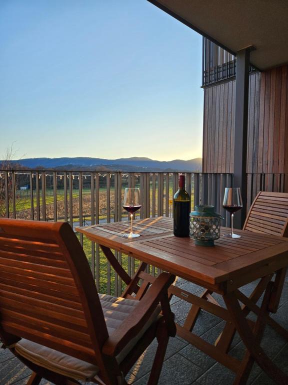 Črniče的住宿－Apartma Ksenija，阳台上的木桌和两杯葡萄酒