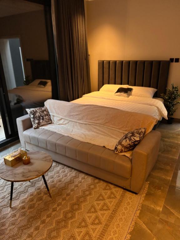 een slaapkamer met een bed met een bank en een tafel bij شقة بدخول ذاتي وجلسة خارجية Midnight Apartment in Riyad