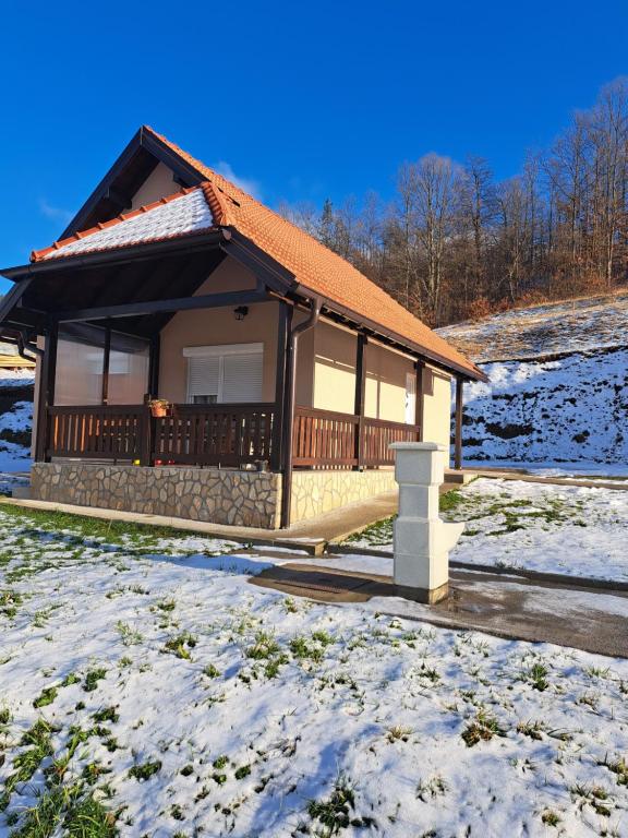 a house with a deck in the snow at Mokrogorska kuca in Mokra Gora