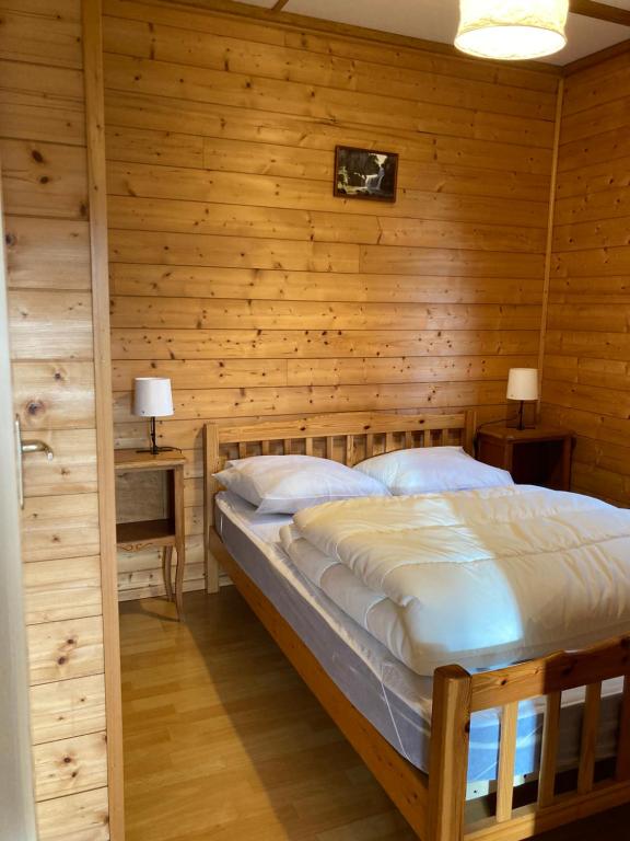 Lac des Rouges Truites的住宿－Camping-Chalets La Favière，卧室配有木墙内的一张床