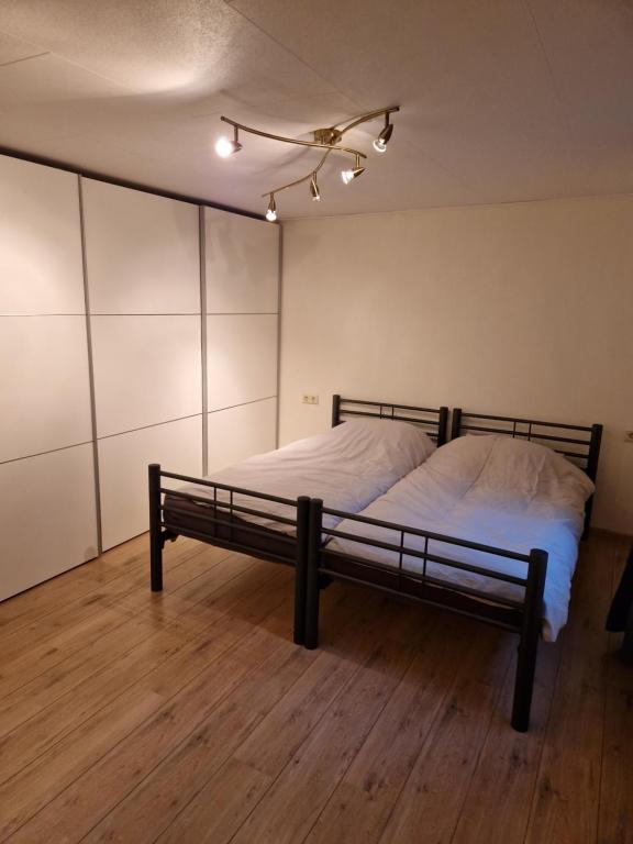 Schlafzimmer mit einem Bett mit weißer Bettwäsche auf einem Holzboden in der Unterkunft Riant huisje in bosrijke omgeving op chaletpark Kempenbos in Diessen