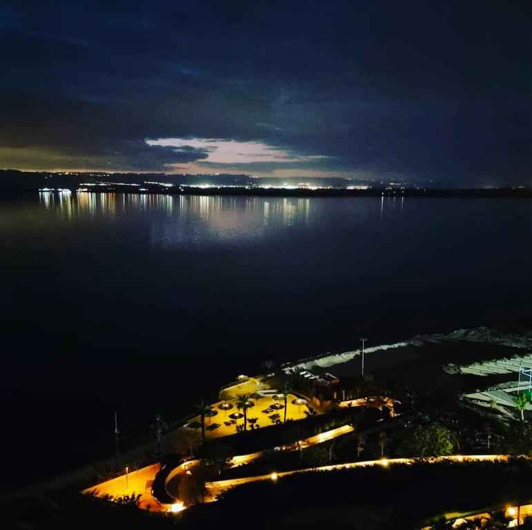 una vista de un gran cuerpo de agua por la noche en DeadSea view apartments Samarah Resort E22, en Amán