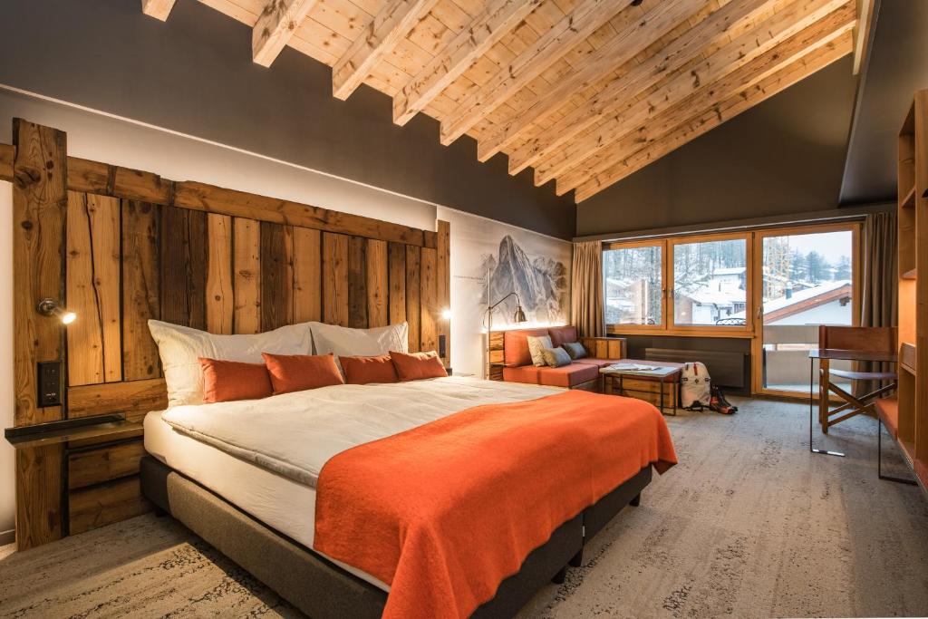 a bedroom with a large bed with an orange blanket at BaseCamp Hotel in Zermatt