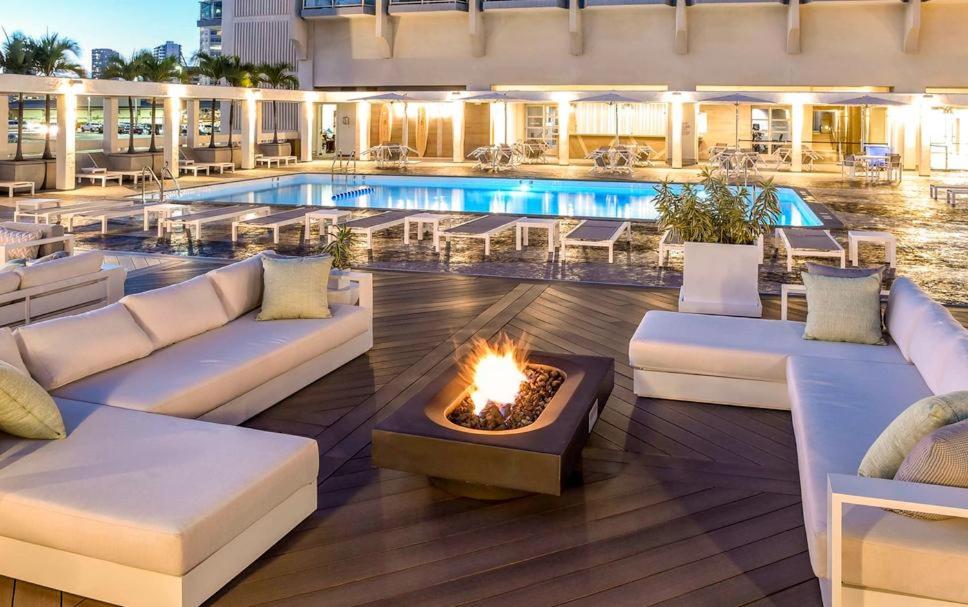 a pool with white couches and a fire pit at Ala Moana Hotel _ Ocean view with balcony in Honolulu