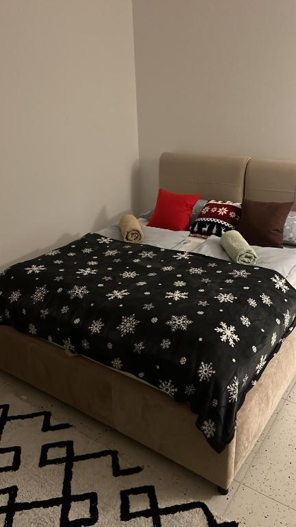 Una cama con una manta negra con flores blancas. en marga_apt en Świnoujście