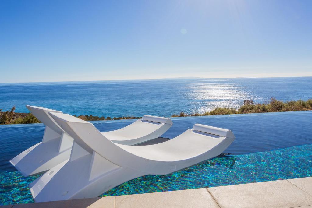 a white bench sitting on top of a swimming pool at Olive and Aloe Villas in Nomikianá