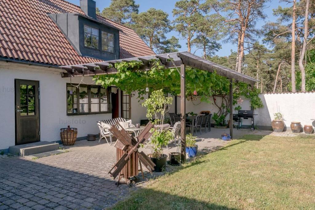 a house with a pergola and a table and chairs at Hela huset västerhejde in Visby