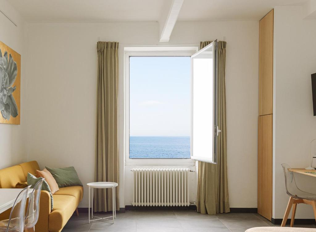 a living room with a couch and a large window at Cà de Mâ Ω Sea Front Apartment in Genoa