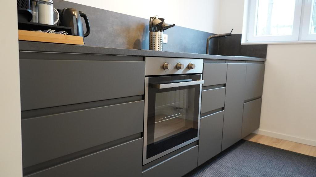 una cocina con horno de acero inoxidable y armarios en Zentral & Modern mit Parkplatz - 30 min bis zur Messe in Köln und Düsseldorf, en Wuppertal