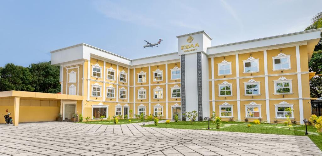 um avião sobrevoa um grande edifício amarelo em ESAA Airport Hotel Kochi em Cochin