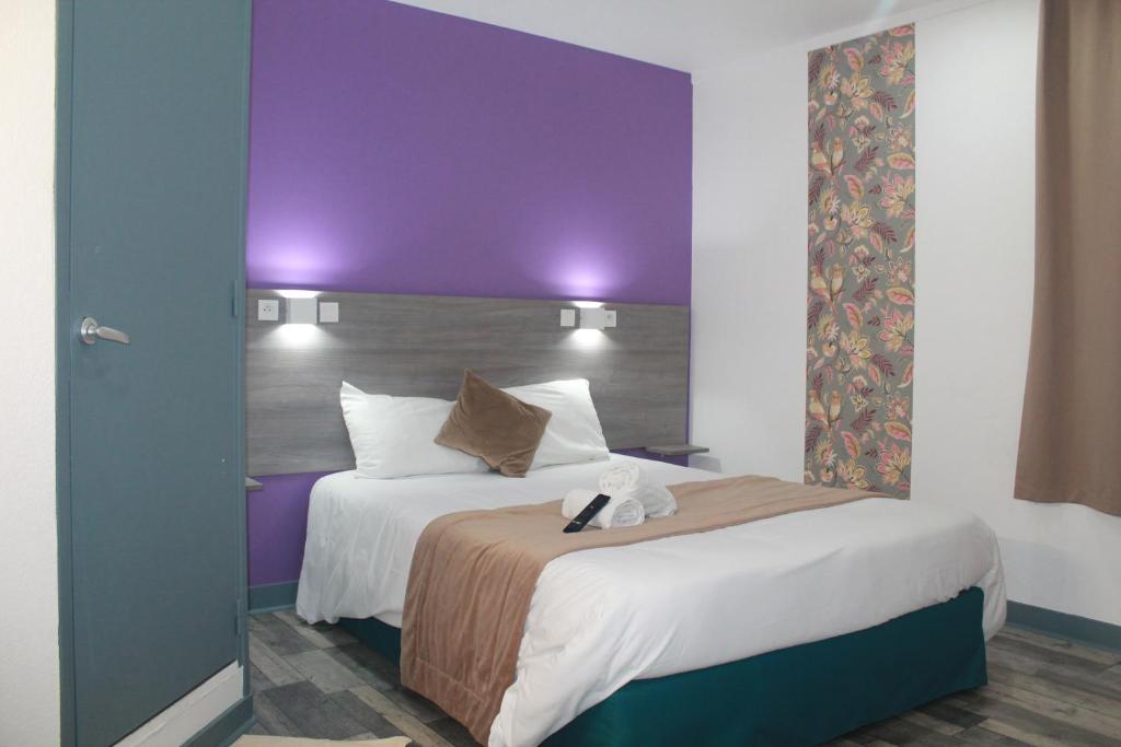 a hotel room with a bed and a purple wall at FASTHOTEL A Dijon in Dijon