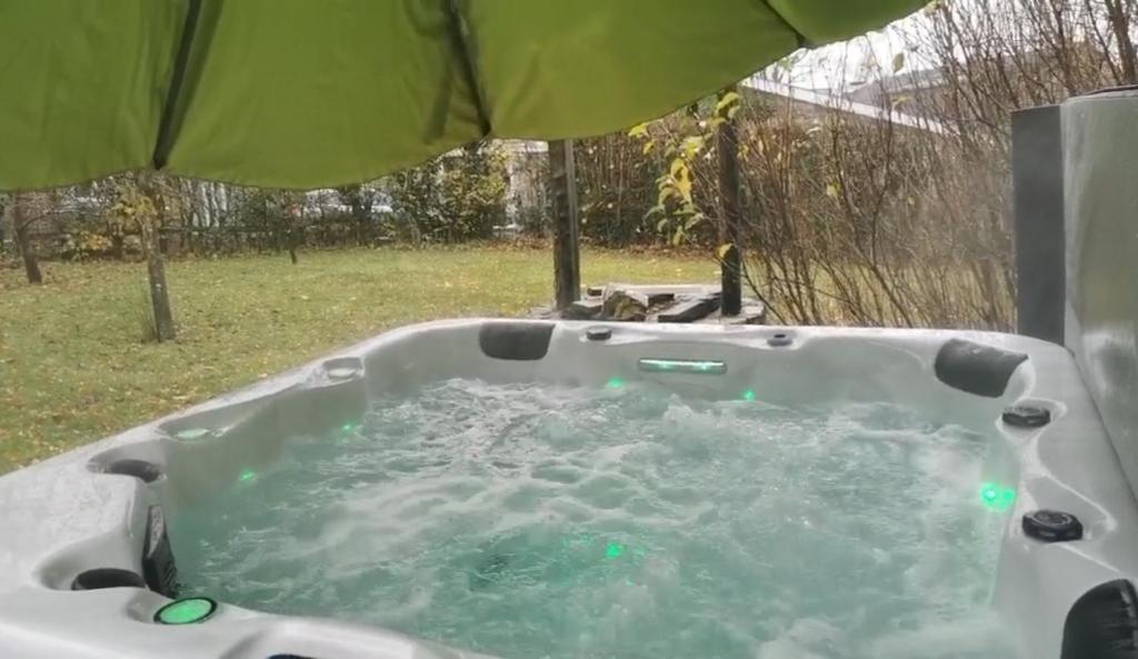 una vasca da bagno riempita d'acqua accanto a un ombrello di Gite Ardennes Au coin du feu jacuzzi sauna et nature a Jalhay