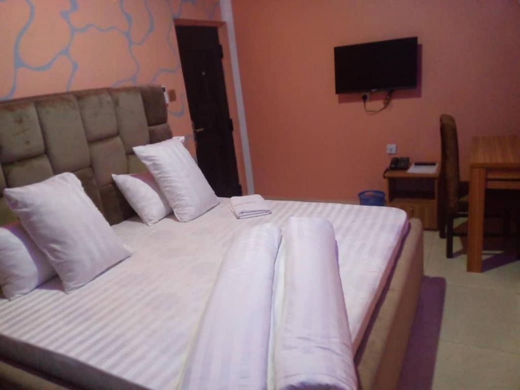 a bedroom with a bed with white pillows and a television at CHARLES GROOVE HOTEL 