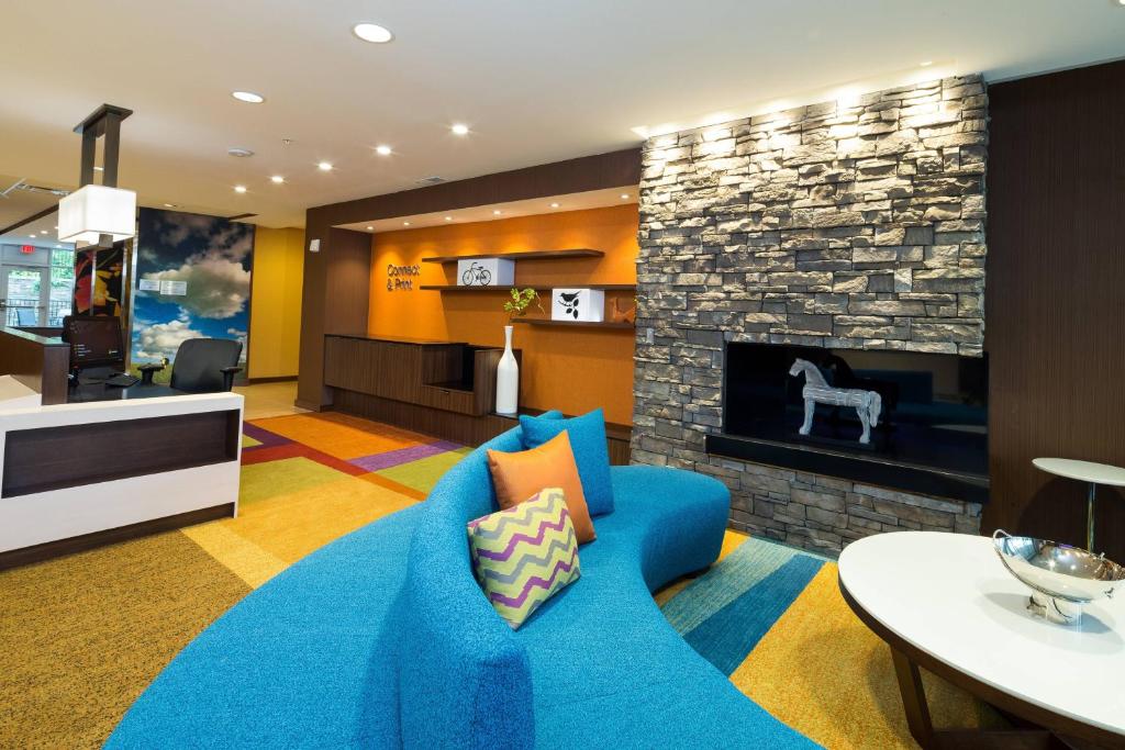 a living room with a blue couch and a fireplace at Fairfield Inn & Suites by Marriott Detroit Chesterfield in Chesterfield