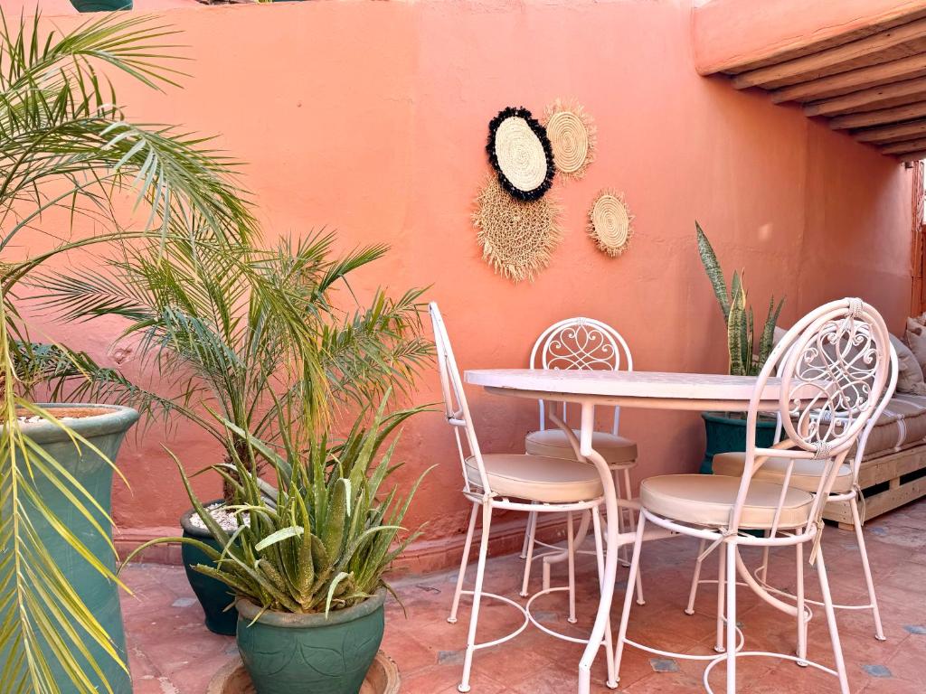 a table and chairs next to a wall with plants at Riad Sanwa in Marrakesh