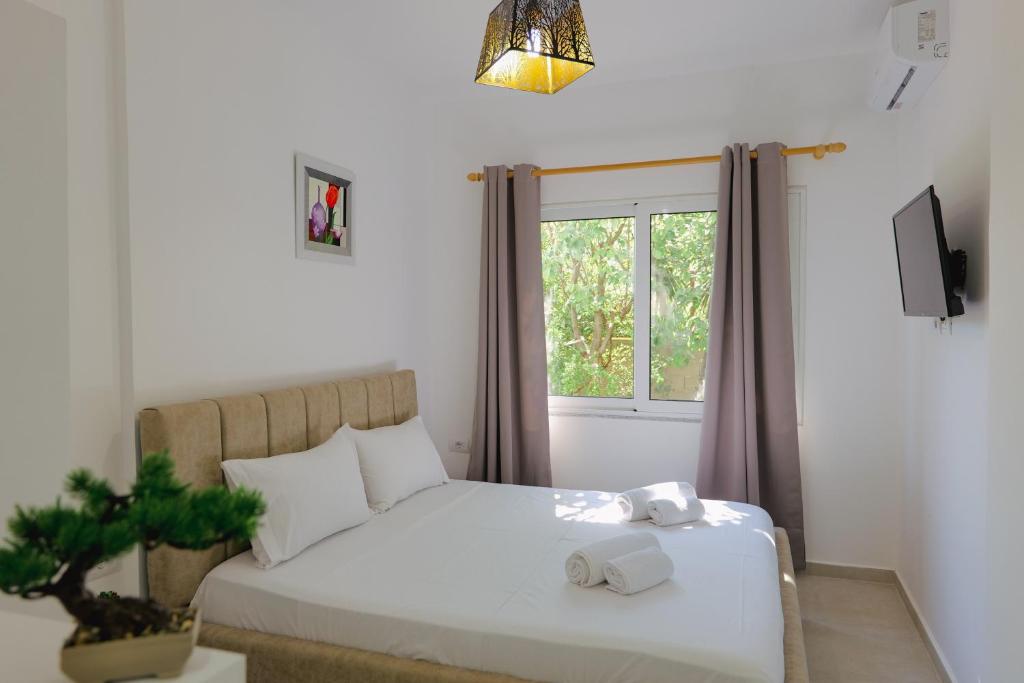um quarto com uma cama branca e uma janela em Relaxing Escape Rooms em Ksamil