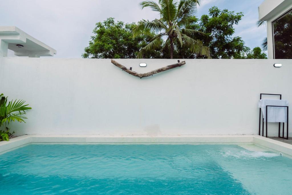a swimming pool in front of a white wall at Trio Villas Watamu in Watamu