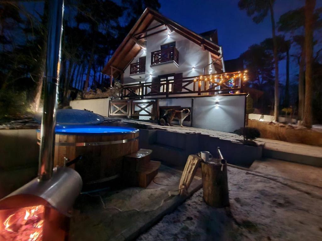 uma casa com uma banheira de hidromassagem em frente à mesma à noite em Hacjenda em Boszkowo-Letnisko