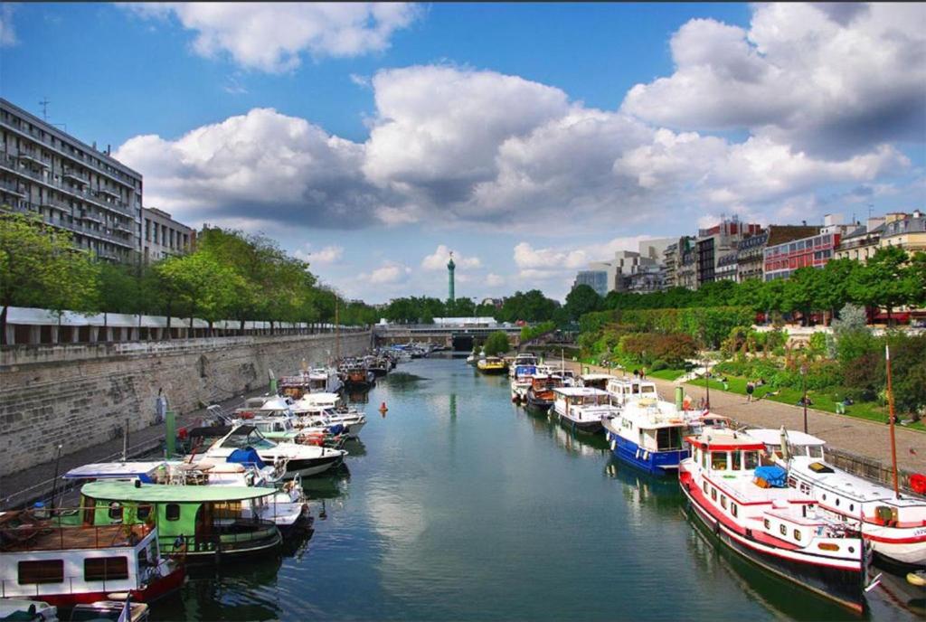 um grupo de barcos está ancorado num rio em Heart of Paris - Entire or Private Room Apartment - Bastille & Marais em Paris