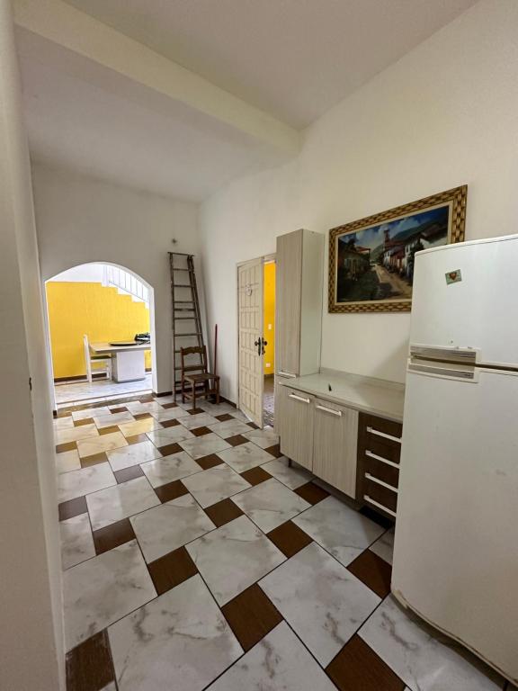 a kitchen with a refrigerator and a floor with tiles at Hostel Encanto de Mongaguá in Mongaguá