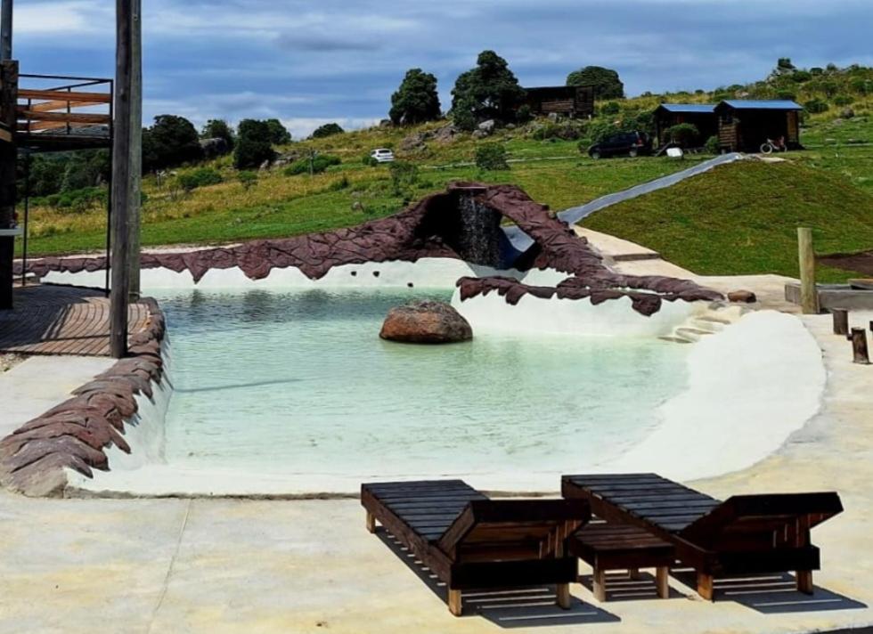 a pool of water with two benches in front of it at Valle de la Luna in Tandil