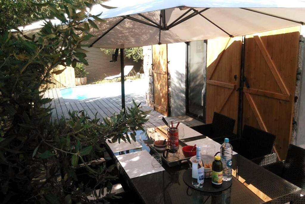 um pátio com uma mesa e um guarda-chuva em La Bergerie Nepita avec piscine pour 4 pers. em Porto-Vecchio