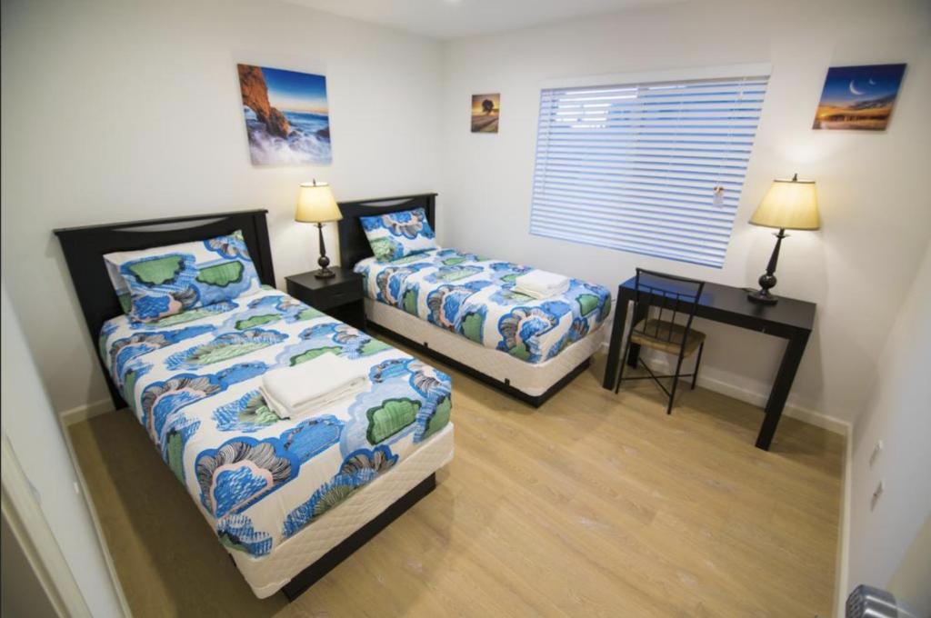 Duas camas num quarto com uma secretária e uma mesa em Shared Living Los Angeles (LAX) em Los Angeles