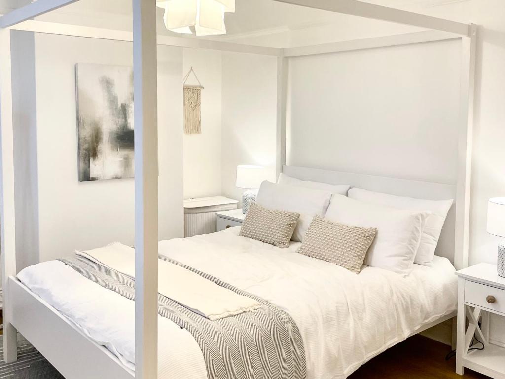 a white bedroom with a white bed with pillows at Windsor Cottage in Amble