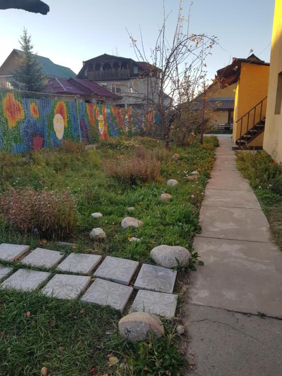 a walkway with rocks in the grass next to a fence at Memo's Boutique Guesthouse in Karakol