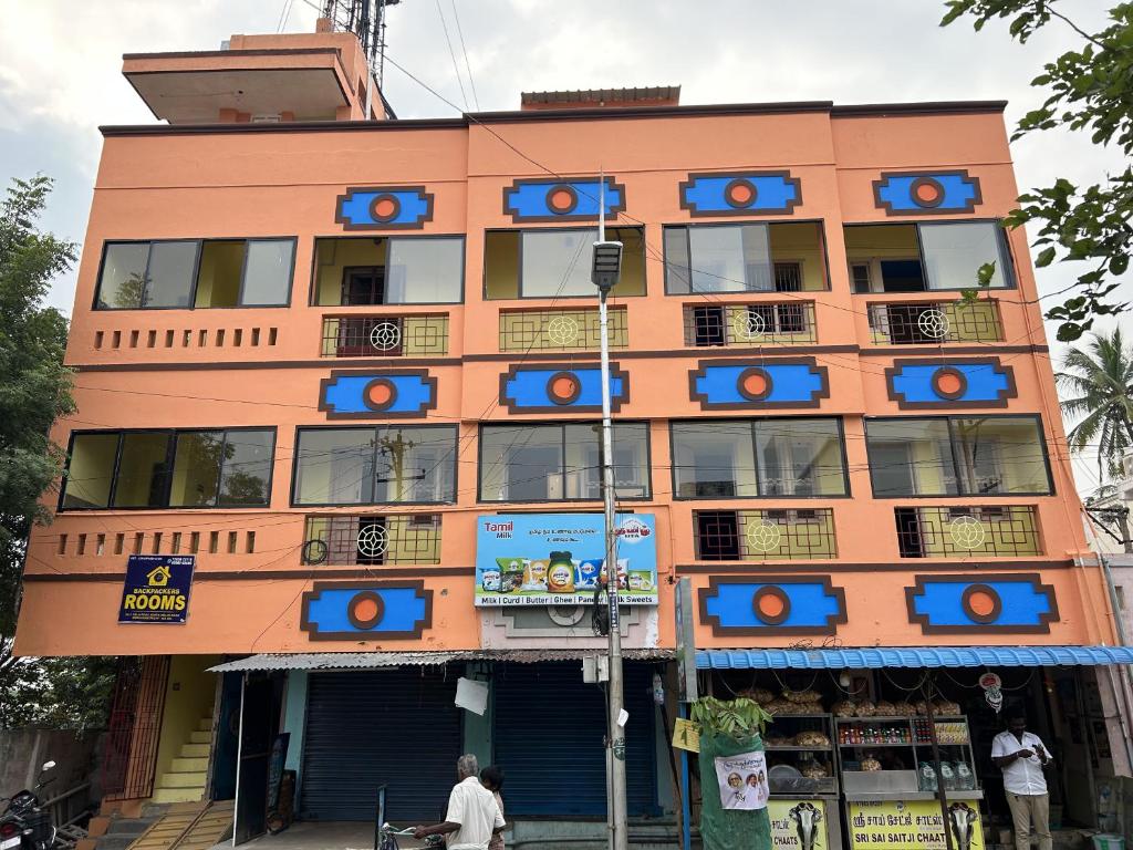 a tall orange building with blue signs on it at The Kaya Backpackers Rooms Srirangam in Tiruchchirāppalli