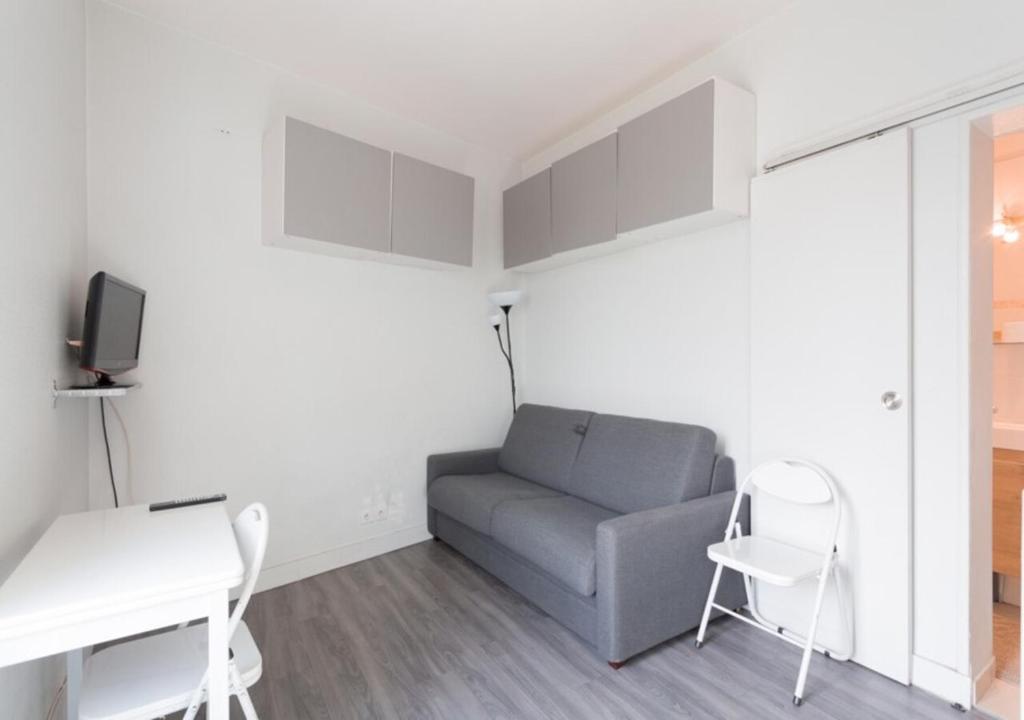 ein Wohnzimmer mit einem Sofa, einem Tisch und Stühlen in der Unterkunft Studio Meublé in Gentilly
