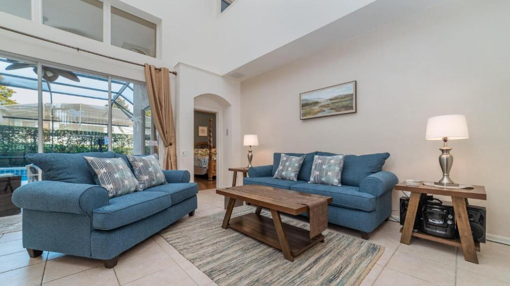 una sala de estar con 2 sofás azules y una mesa. en 6 BR Vacation Home for 12 Guests, en Kissimmee
