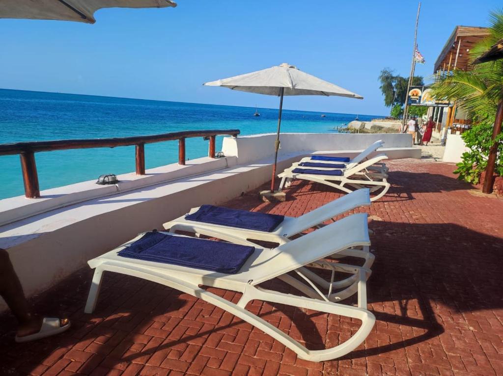 Blue Tides Hotel في نونغوي: كرسيين للصالة ومظلة على شرفة مطلة على المحيط