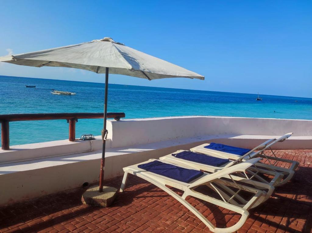 un sillón con sombrilla en la playa en Blue Tides Hotel en Nungwi