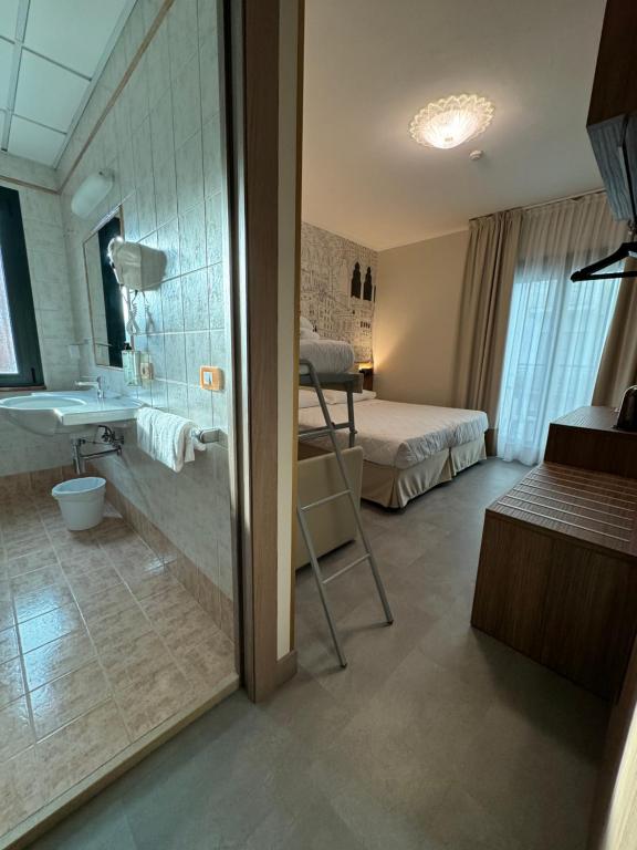 a bathroom with a shower and a bedroom with a bed at Hotel Marco Polo in Lido di Jesolo