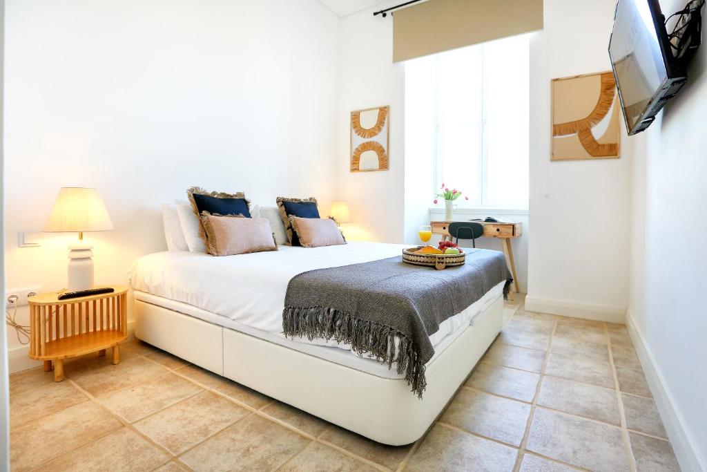 una camera da letto con un grande letto bianco e una televisione di Hot Breeze Apartment a Faro