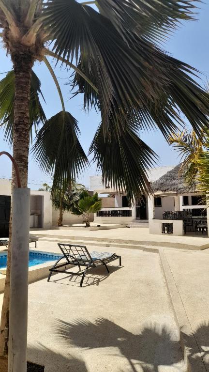 een bank naast een palmboom naast een zwembad bij chez André in Sali Tapé