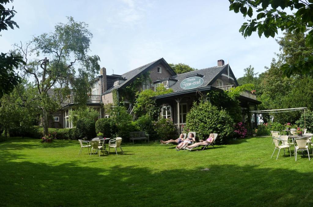 a group of people sitting on the lawn in front of a house at Hotel-Pension Zoom-Oord in Renesse