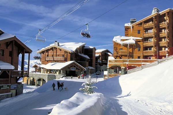 duas pessoas a andar de teleférico na neve em appartement ski au pied residence altineige val thorens em Val Thorens