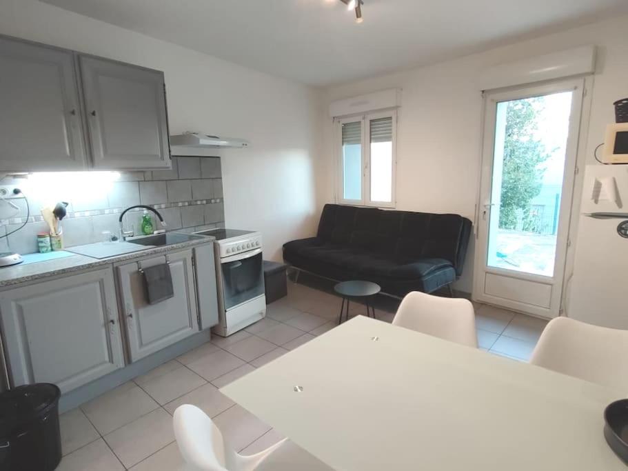 eine Küche und ein Wohnzimmer mit einem Sofa und einem Tisch in der Unterkunft T2 aux portes des Cévennes in Lédignan