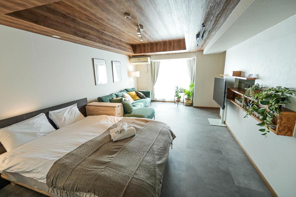 1 dormitorio con 1 cama grande y 1 sofá en AONO STAY SAPPORO, en Sapporo