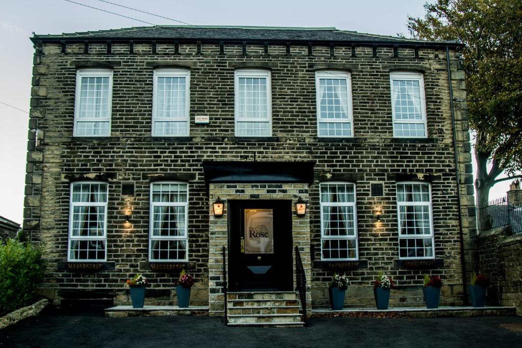 a brick house with a black door and windows at The Rose Bed and Breakfast in Stainland