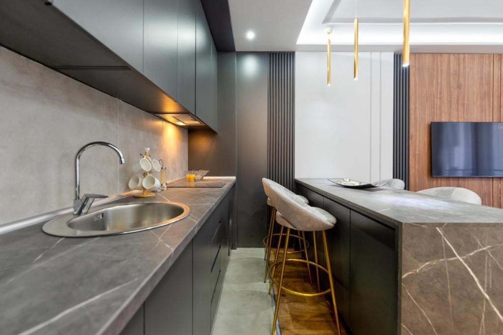uma cozinha com um lavatório e um balcão com cadeiras em Mans lux 8 Apartman em Zlatibor