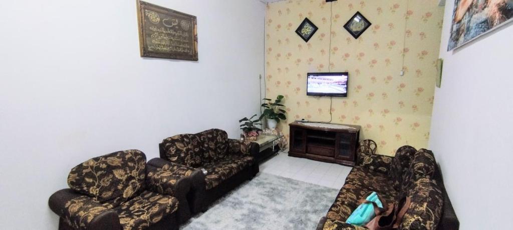 a living room with two couches and a tv at Homestay D'Murni in Kampung Gurun