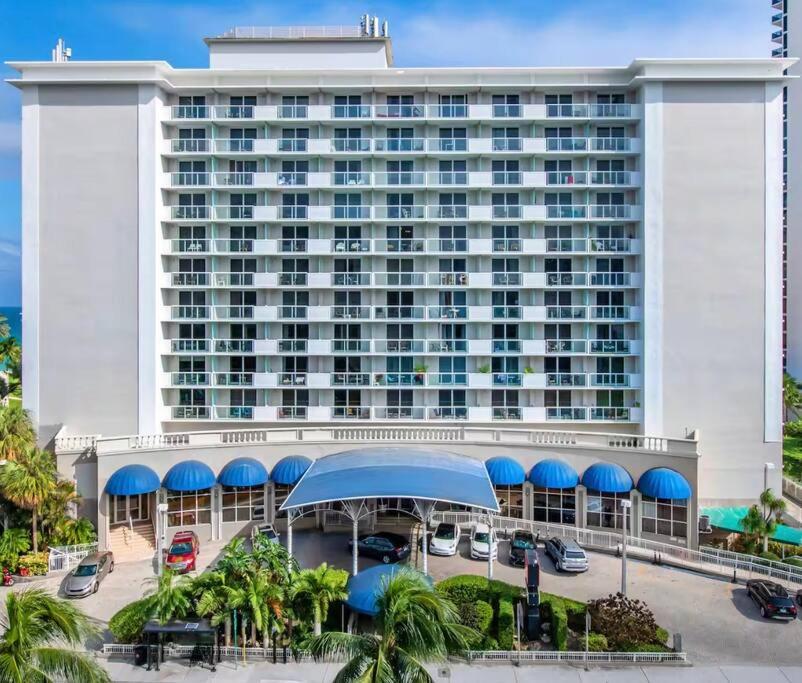 um grande edifício de hotel com estacionamento e palmeiras em Charming seaside studio for 4 people! - Rate included resort fee-Parking fee not included- em Sunny Isles Beach