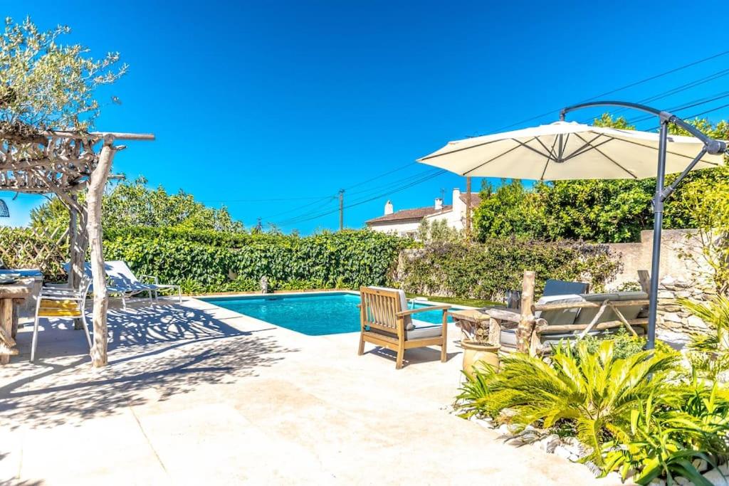 une terrasse avec une table, un parasol et une piscine dans l'établissement Villa La Bastide l Authentic & Pool l Shellter Rentals, à Saint-Tropez