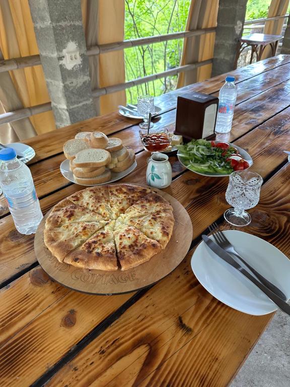 a wooden table with a pizza and plates of food at Martvili canyon cottage in Gachedili