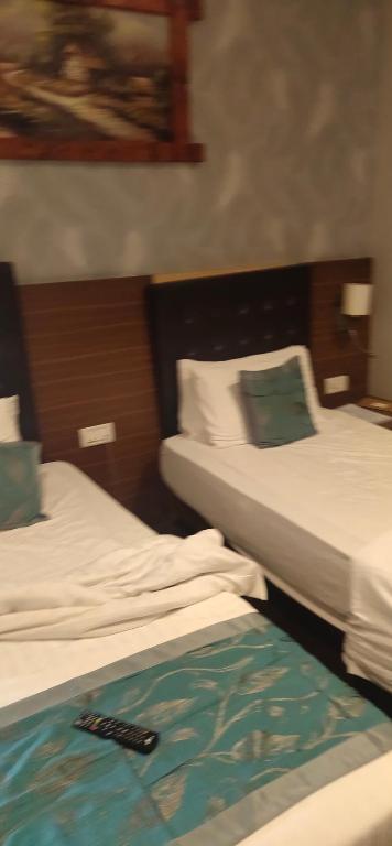 two beds in a hotel room with a remote at Hilltone panorama bungalow resort matheran in Matheran