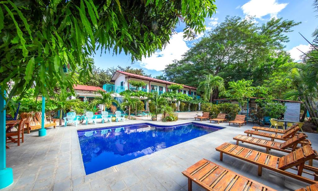 una piscina con sillas de madera y una casa en Hotel Diversion Tropical, en Brasilito